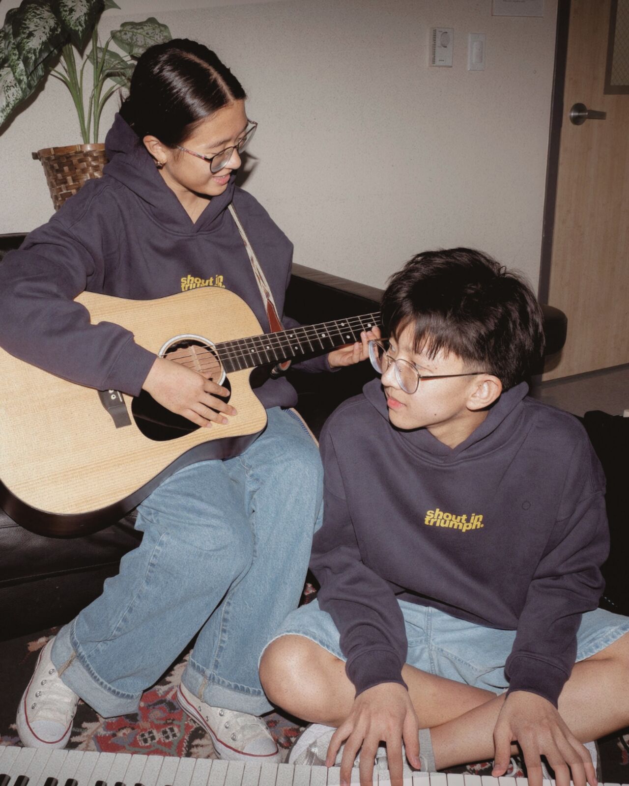 Two students in shout in triumph hoodies with guitar and keys