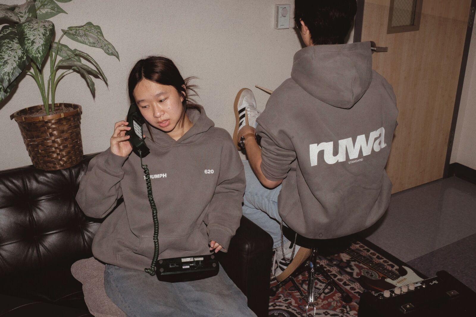 Student on a vintage phone in the Triumph 620 hoodie beside a friend in the Ruwa Standard hoodie