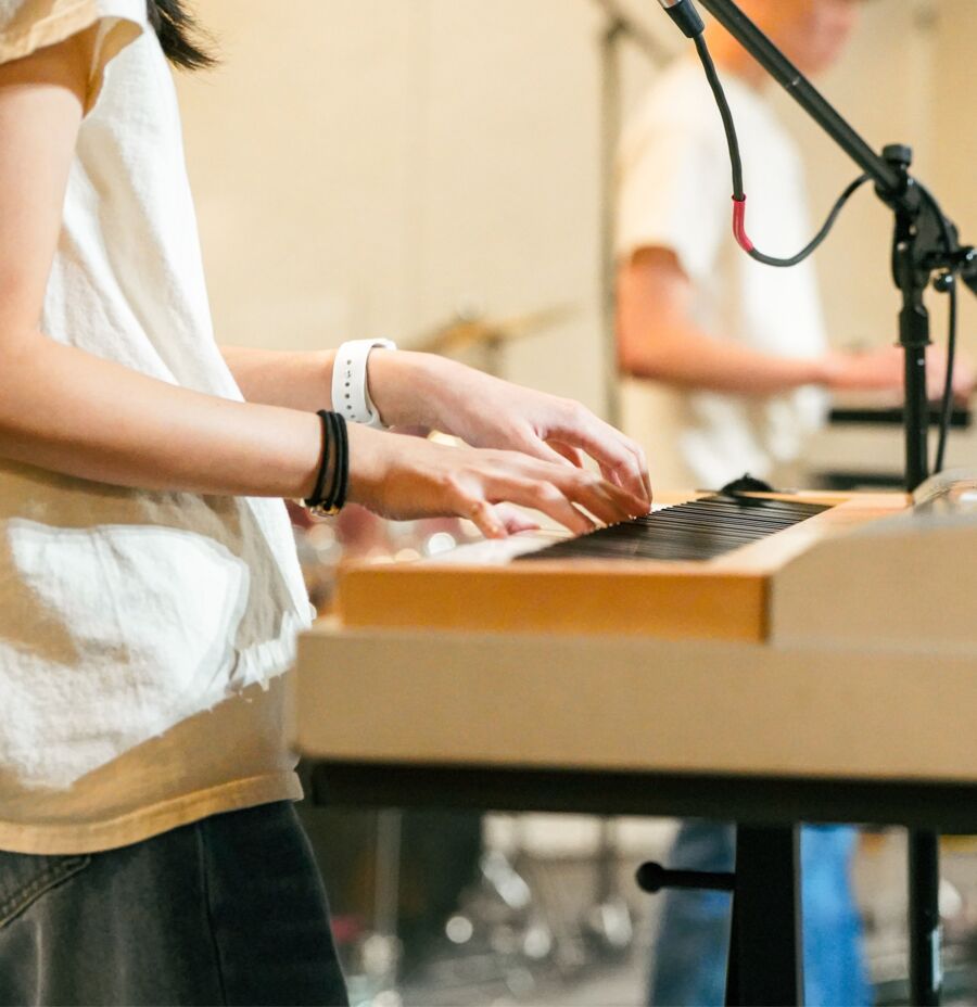 Student playing keyboard with a worship band