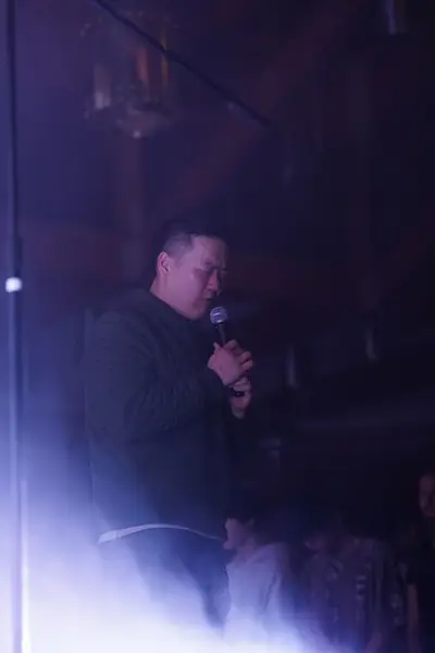 Leader praying into a microphone with eyes closed